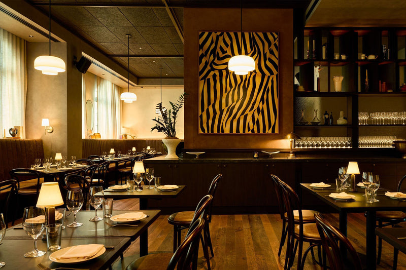 NEOZ Victoria cordless lamp in aged brass illuminating a dining setting at Bistro Saine in Auckland.